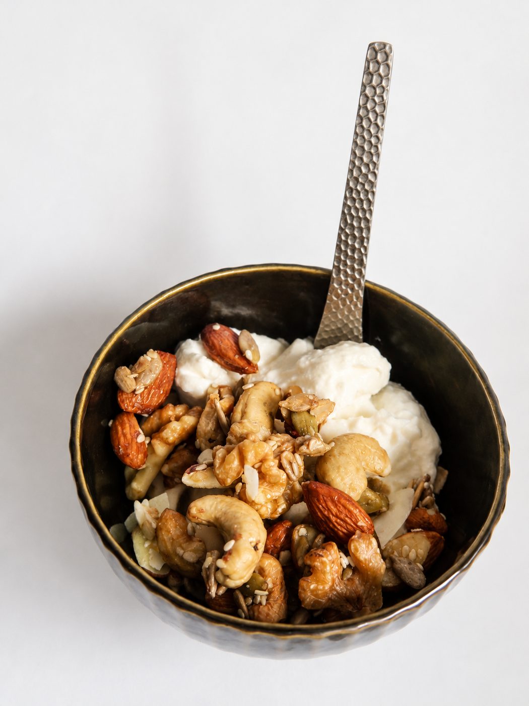 Bowl oscuro con yogur y granola, visto desde arriba, con una cuchara